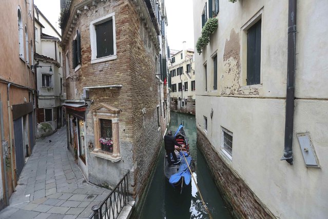 A gondolier rows a gondola in a narrow canal in Venice February 1, 2015. The sleek black gondolas that whisper through Venice bear the hallmarks of a tiny but proud group of artisans striving to keep alive the traditional building methods for the floating city's most recognizable symbol. (Photo by Stefano Rellandini/Reuters)