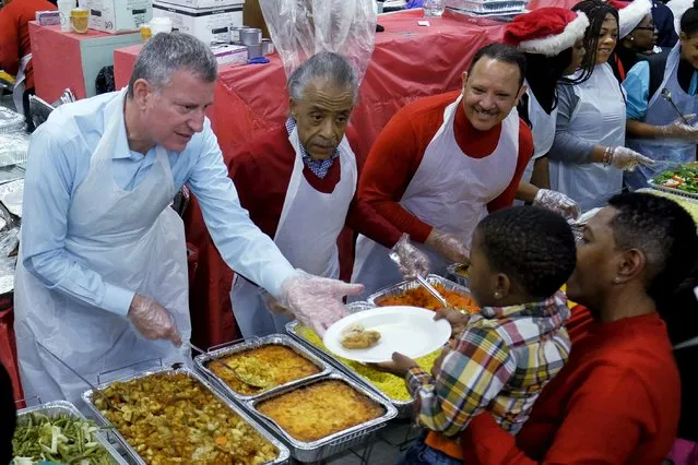 New York City Mayor Bill de Blasio (L) and civil rights activist Al Sharpton (2nd L) serve food to children and people while they take part in a event celebrating Christmas at the National Action Network in Harlem, New York December 25, 2015. (Photo by Eduardo Munoz/Reuters)