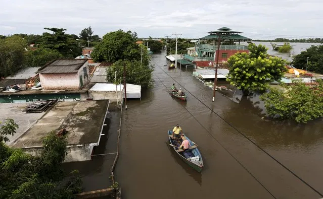 Men travel on a boat near flood-affected houses in Asuncion, December 27, 2015. (Photo by Jorge Adorno/Reuters)