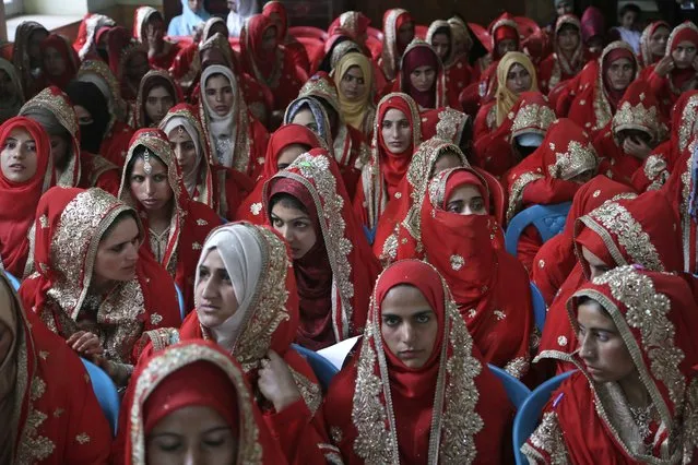 In this Sunday, July. 15, 2018, file photo, Kashmiri Shiite Muslim brides sit for a mass marriage event in Srinagar, Indian controlled Kashmir. Mass weddings in India are organized by social organizations primarily to help the economically backward families who cannot afford the high ceremony costs as well as the customary dowry and expensive gifts that are still prevalent in many communities. (Photo by Mukhtar Khan/AP Photo)