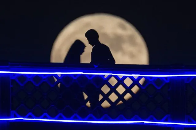 A couple cross the Al-Shuhada'a bridge over the Tigris River as the full moon rising in Baghdad, Iraq, Monday, July 3, 2023. (Photo by Hadi Mizban/AP Photo)