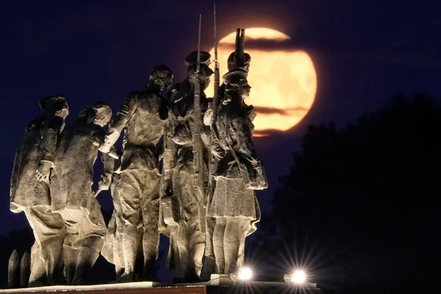 A super moon rises behind a Soviet-era monument for defenders of Leningrad, now St. Petersburg, in World War II, in St. Petersburg, Russia, early Tuesday, July 4, 2023. (Photo by Dmitri Lovetsky/AP Photo)