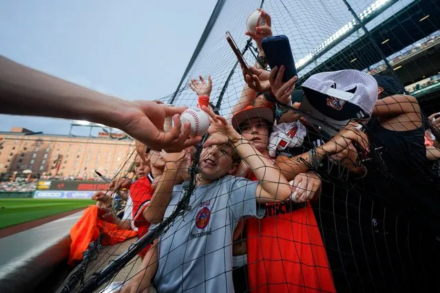 Young fans gather near netting as Baltimore Orioles shortstop Gunnar Henderson, left, signs autographs prior to a baseball game against the New York Yankees, Saturday, July 29, 2023, in Baltimore. (Photo by Julio Cortez/AP Photo)