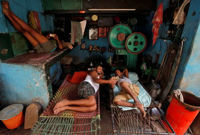 Workers watch their mobile phones as they rest in cots during a break inside a workshop in Kolkata, India August 28, 2018. (Photo by Rupak De Chowdhuri/Reuters)