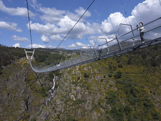 People walk across a narrow footbridge suspended across a river canyon, which claims to be the world's longest pedestrian bridge, in Arouca, northern Portugal, Sunday, May 2, 2021. The Arouca Bridge inaugurated Sunday, offers a half-kilometer (almost 1,700-foot) walk across its span, some 175 meters (574 feet) above the River Paiva. (Photo by Sergio Azenha/AP Photo)