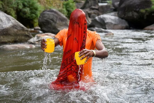 A devotee collects water, which is considered holy, from the Bagmati river during the “Bol Bom” (Say Shiva) pilgrimage during the holy month of Shrawan in Kathmandu, Nepal on July 31, 2023. (Photo by Monika Malla/Reuters)