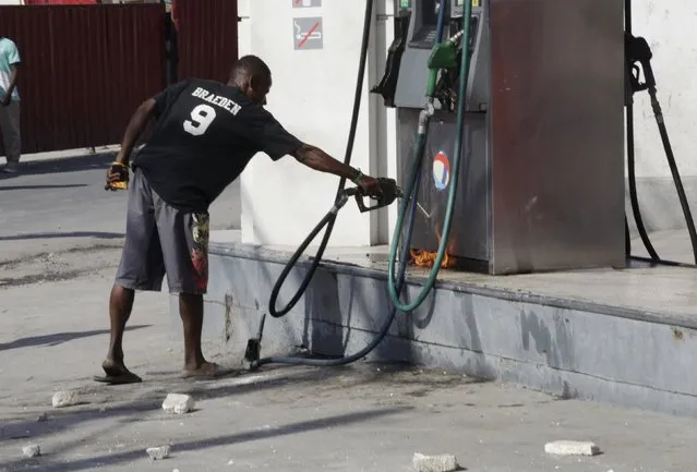 A protester tries to pump gasoline to feed a little fire at a gas station during a demonstration against the electoral process in Port-au-Prince, Haiti, January 18, 2016. Haiti's delayed presidential run-off election will take place on January 24. (Photo by Andres Martinez Casares/Reuters)