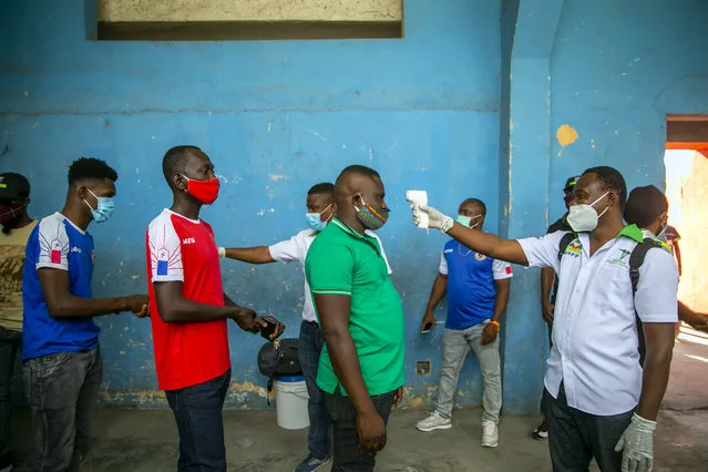 Health ministry workers check the temperature of mask-wearing fans as a precaution against the spread of the new coronavirus, before entering the stadium prior to the start of the CONCACAF World Cup qualifying soccer match between Haiti and Belize in Port-au-prince, Haiti, Thursday, March 25, 2021. (Photo by Dieu Nalio Chery/AP Photo)