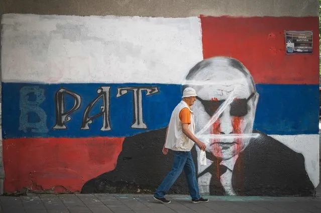 A pedestrian walks past a partly vandalized mural depicting Russian President Vladimir Putin in Belgrade on June 2, 2022. At a time when most European countries are struggling to detach themselves of Russian fossil fuels, EU candidate Serbia announced a new gas deal that could further lock it into political dependence on Moscow The Balkan country secured “a very favourable” contract with Russia, Serbian president Aleksandar Vucic said after a phone call with Vladimir Putin last Sunday. (Photo by Andrej Isakovic/AFP Photo)