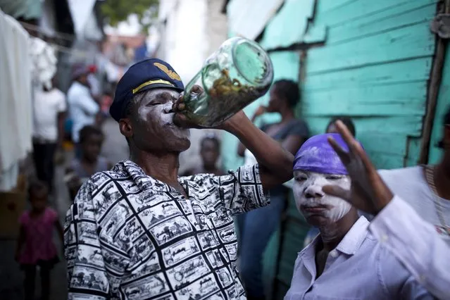 In this Oct.ober 31, 2018 photo, Raynold Alexandre, a voodoo priest, who is supposed to be possessed the Gede spirit, drinks with his daughter Darline Alexandre, also voodoo priestess, during Haiti's annual Voodoo festival Fete Gede, in Cite Soleil slum, in Port-au-Prince, Haiti. Alexandre and his wife Auguste are well known voodoo priests and three of their six children are also voodoo priests. (Photo by Dieu Nalio Chery/AP Photo)