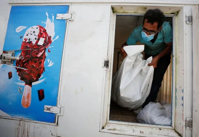 A man man works on moving the body of a Palestinian, who was killed in Israeli strikes, from an ice cream truck where it was kept, as the hospital morgues are packed, amid the ongoing Israeli-Palestinian conflict, in the central Gaza Strip on October 15, 2023. (Photo by Reuters/Stringer)