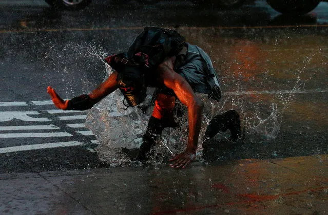 A man splashes in a puddle in Times Square during a heavy midday downpour in New York, July 17, 2018. (Photo by Brendan McDermid/Reuters)