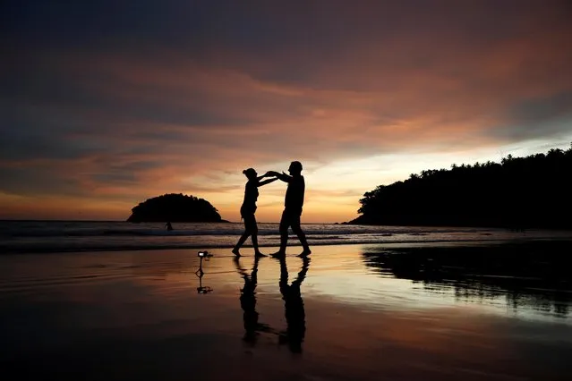 Local residents Stavros from Greece and Valina from Russia dance on an almost empty Kata beach as Phuket reopens to overseas tourists, allowing foreigners fully vaccinated against the coronavirus disease (COVID-19) to visit the resort island without quarantine, in Phuket, Thailand on July 1, 2021. (Photo by Jorge Silva/Reuters)