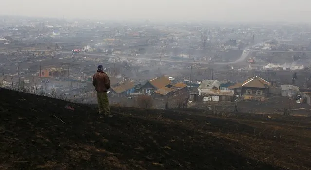A man looks downhill at the settlement of Shyra, damaged by recent wildfires, in Khakassia region, April 13, 2015. Wildfires in the Russian region of Khakassia in southern Siberia have killed 15 people and caused damage worth at least $96 million, the region's leader said on Monday. (Photo by Ilya Naymushin/Reuters)