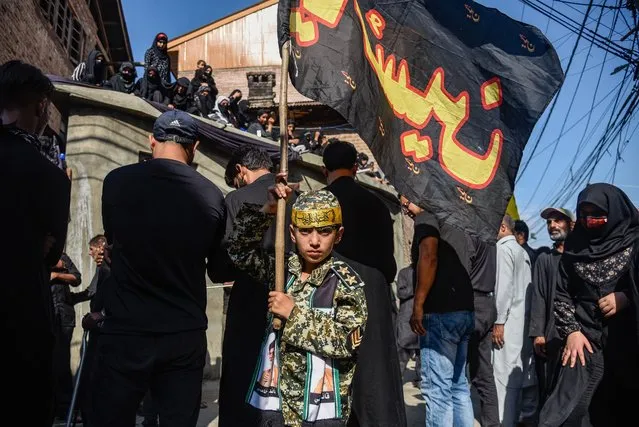 A Kashmiri Shia Muslim boy dressed as IRGC (Iran's Islamic Revolutionary Guard Corps) holds an Islamic flag during the Ashura procession in Srinagar on August 20, 2021. Shia Muslim believers offer prayers, beat their chests while chanting religious slogans and distribute religious food called “nazri”, as they reenact aspects of the killing of Imam Hussain and his 72 followers in 680AD in Karbala on Ashura (the 10th of Muharram), in modern-day Iraq, by the far larger armies of the Yazid. Imam Hussain is revered among Shia's as the “Lord of the Martyrs”, whose resistance and willingness to die for his religious faith in the face of overwhelming force is venerated by Shia's as a model for daily life. (Photo by Idrees Abbas/SOPA Images/Rex Features/Shutterstock)