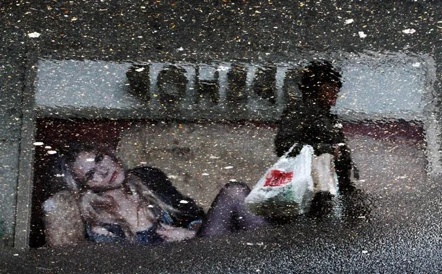 A shopper is reflected next to the window of a clothing store in a puddle of water downtown Madrid January 19, 2010. This picture has been rotated 180 degrees. (Photo by Susana Vera/Reuters)