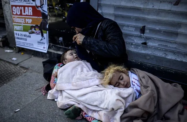 A Syrian refugee woman begs with her children on the street  in the Beyoglu district of Istanbul on April 17, 2015. (Photo by Bulent Kilic/AFP Photo)
