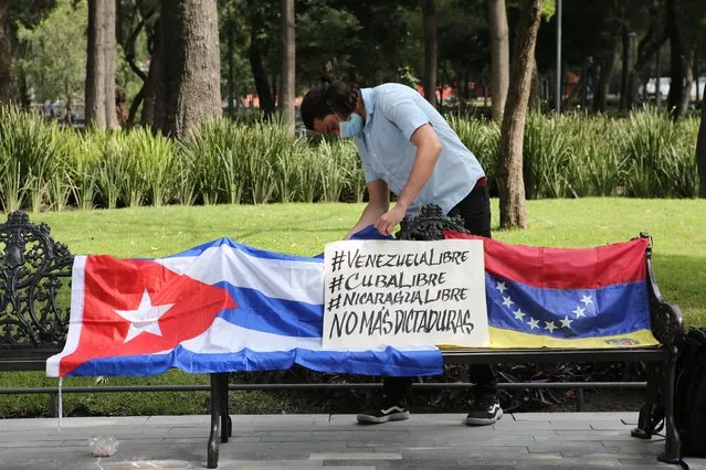 A Cuban man arranges a Cuban flag next to a Venezuelan national flag during a small demonstration in Alameda Park against the participation of Venezuela’s President Nicolas Maduro in the Community of Latin American and Caribbean States, CELAC, summit in Mexico City, Saturday, September 18, 2021. CELAC has only existed for 10 years and is more left-leaning, having remained on good terms with countries including Cuba, Venezuela and Nicaragua. (Photo by Ginnette Riquelme/AP Photo)