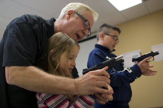 Instructor Jerry Kau shows student Joanna Zuber how to load a magazine into a handgun alongside Sam Minnifield (L-R) during a Youth Handgun Safety Class at GAT Guns in East Dundee, Illinois, April 21, 2015. (Photo by Jim Young/Reuters)