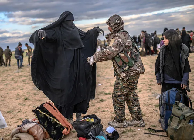 A member of the Kurdish-led Syrian Democratic Forces (SDF) searches a woman after she left the IS group's last holdout of Baghouz, in Syria's northern Deir Ezzor province on February 27, 2019. (Photo by Bülent Kılıç/AFP Photo)