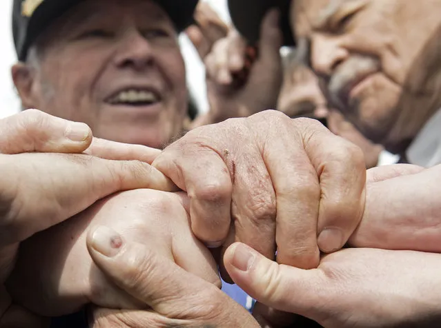 Russian veteran Victor Maximov, right, and the US veteran Chet Yastrzemski of Southhampton, New York, left, hold hands with others during the 70th anniversary celebrations of the so-called Elbe Day in Torgau, eastern Germany, Saturday, April 25, 2015. (Photo by Jens Meyer/AP Photo)