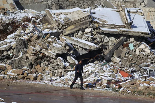 A boy walks near snow-covered rubble of damaged buildings in al-Rai town, northern Aleppo countryside, Syria January 28, 2017. (Photo by Khalil Ashawi/Reuters)