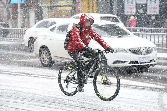 A youth rides a bicycle during heavy snowfall in Huai'an, in eastern China's Jiangsu province on February 4, 2024. (Photo by AFP Photo/China Stringer Network)