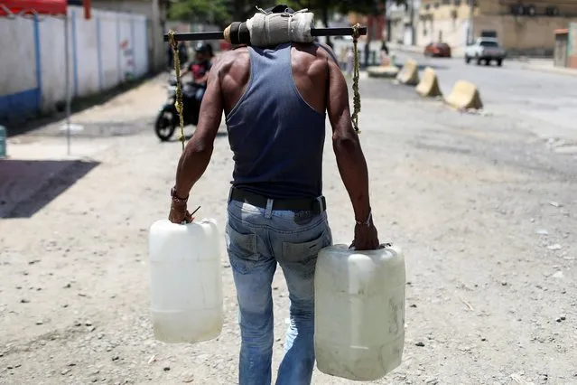 A man carries containers filled with water at a desalination plant in La Guaira, March 13, 2019. (Photo by Manaure Quintero/Reuters)