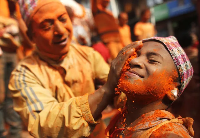 A Nepalese smears “sindoor” or vermillion powder, to a boy during Sindoor Jatra festival in Bhaktapur, Nepal, Tuesday, April 15, 2019. Devotees mark the festival by playing traditional drums, singing, dancing and carrying chariot of various deities around town while throwing sindoor, vermillion powder, to welcome the advent of spring and the New Year. (Photo by Niranjan Shrestha/AP Photo)