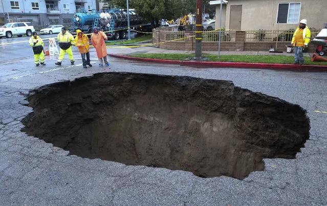 Inspectors examine a sinkhole Saturday, February 18, 2017, in Studio City, north of Los Angeles. Two vehicles fell into the 20-foot sinkhole on Friday night and firefighters had to rescue one woman who escaped her car but was found standing on her overturned vehicle. (Photo by Ringo H.W. Chiu/AP Photo)