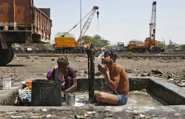 A man bathes as a woman washes her clothes at municipal taps along railway tracks at a yard in Ahmedabad, India, April 6, 2016. (Photo by Amit Dave/Reuters)