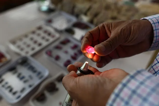 This photo taken on May 17, 2019 shows a buyer inspecting a ruby at the gems market in Mogok town, north of Mandalay. (Photo by Ye Aung Thu/AFP Photo)