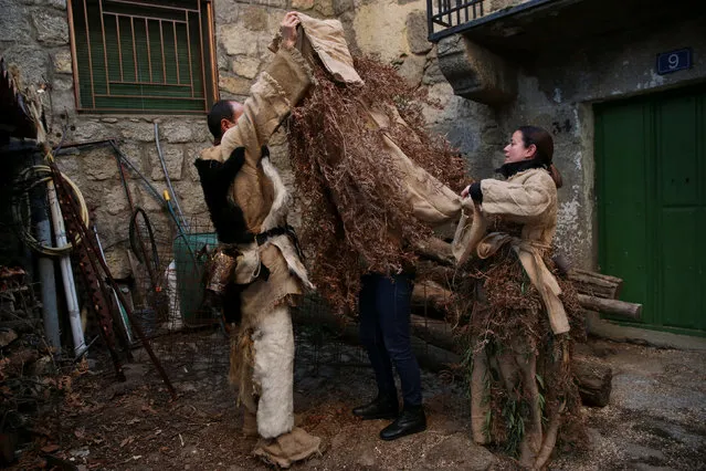 Mariano Casillas (L) and his wife Marta Vega help Cristina Casillas get dressed as traditional carnival characters “Harramachos”, who wear cowbells, animal antlers and agricultural decor and are thought to ward off evil spirits and awaken the coming spring, during a carnival celebration in the village of Navalacruz, Spain, February 25, 2017. (Photo by Susana Vera/Reuters)