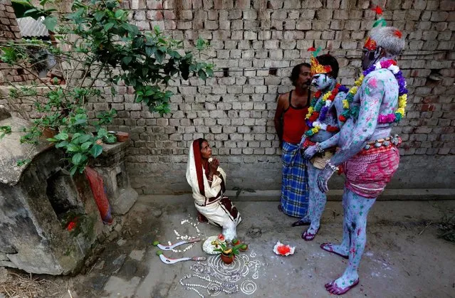 A woman seeks blessings from devotees with their bodies painted, before the start of a ritual as part of the annual Shiva Gajan religious festival at Sona Palasi village, in West Bengal, India, April 11, 2016. (Photo by Rupak De Chowdhuri/Reuters)