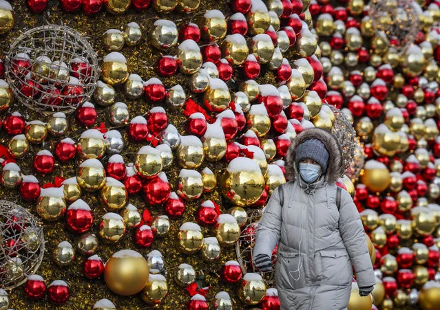 A Russian woman wearing protective face mask walks on the street in Moscow, Russia, 22 December 2021. Russia reported 25,264 new coronavirus infections over the past 24 hours. (Photo by Yuri Kochetkov/EPA/EFE)