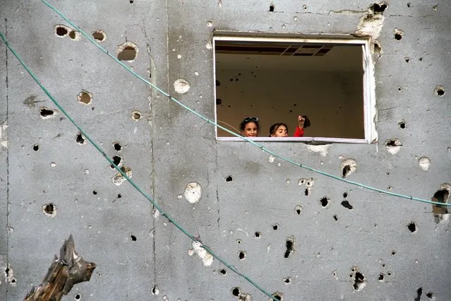 Palestinian children look on from a window during Eid al-Fitr, amid the ongoing conflict between Israel and the Palestinian Islamist group Hamas, in Gaza City on April 11, 2024. (Photo by Mahmoud Issa/Reuters)