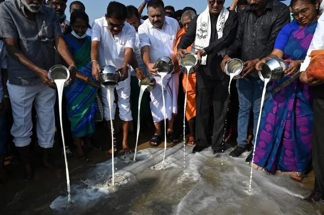 People pour milk in to seas as they perform rituals during a ceremony for the victims of the 2004 tsunami at Pattinapakkam Beach in Chennai on December 26, 2021. (Photo by Arun Sankar/AFP Photo)