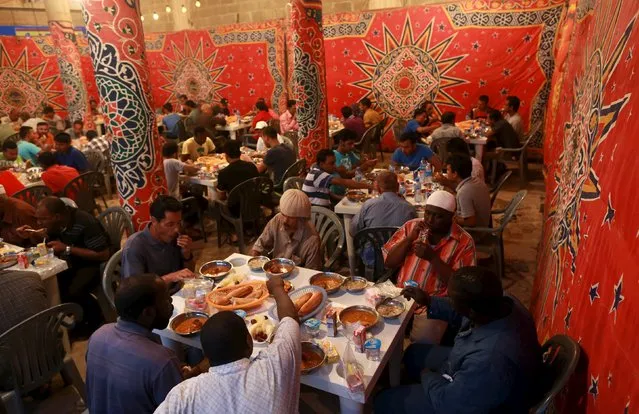 People eat their Iftar (breaking of fast) meal at tables offering free food set up by a charity during the holy fasting month of Ramadan in Benghazi, Libya June 27, 2015. (Photo by Esam Omran Al-Fetori/Reuters)