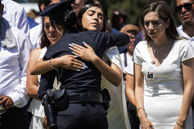 A Los Angeles Police Department officer hugs Anahi Diaz, center, after placing a flower on her brother Officer Juan Jose Diaz's coffin during the funeral at Forest Lawn Hollywood Hills cemetery, Monday, August 12, 2019, in Los Angeles. Diaz was killed while off duty in Lincoln Heights after visiting a taco stand. (Photo by Sarah Reingewirtz/The Orange County Register via AP Photo)
