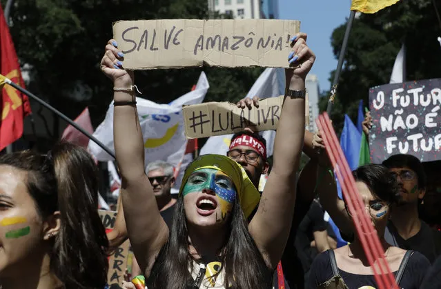 A student holds a sign with a message that reads in Portuguese: “Save the Amazon” during a protest against budget cuts on public education carried out by President Jair Bolsonaro's administration and in defense of the Amazon rainforest in Rio de Janeiro, Brazil, Saturday, September 7, 2019. Students wore black jerseys symbolizing the mourning for the Amazon and education. (Photo by Silvia Izquierdo/AP Photo)