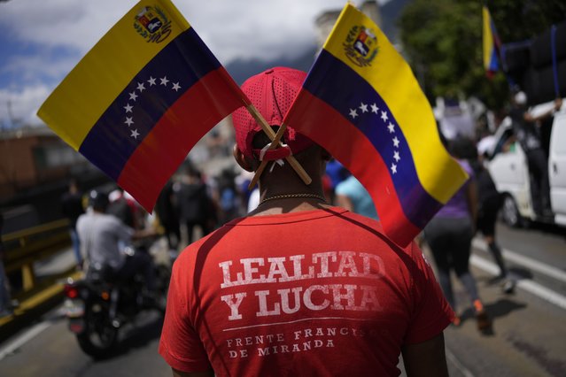 A government supporter, wearing a T-shirt with a message that reads in Spanish: “Loyalty and struggle”, takes part in a march marking Youth Day, in Caracas, Venezuela, Saturday, February 12, 2022. The annual holiday commemorates the young people who accompanied heroes in the battle for Venezuela's independence. (Photo by Matias Delacroix/AP Photo)