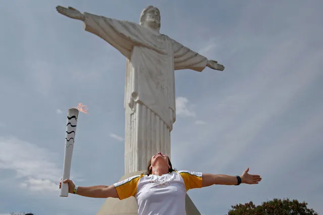 Resident Jane Magriotis opens her arms in front of the Christ statue as she takes part in the Olympic Flame torch relay in Araxa, Minas Gerais state, Brazil May 8, 2016. (Photo by Fernando Soutello/ReutersCourtesy of Rio2016)
