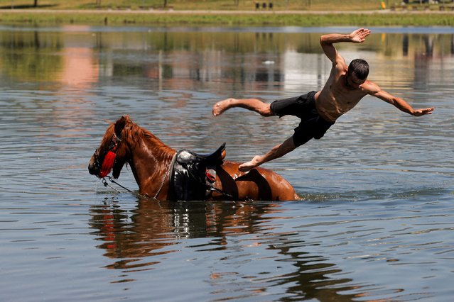 A man jumps from a horse into the Iber River to cool off from hot weather in Mitrovica, Kosovo on June 18, 2024. (Photo by Valdrin Xhemaj/Reuters)