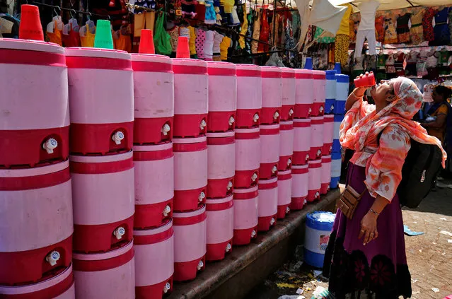 A woman drinks water from a public water facility at a roadside market on a hot day in Ahmedabad, April 18, 2017. (Photo by Amit Dave/Reuters)