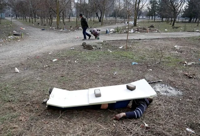 The body of a person lies on the ground in the besieged southern port city of Mariupol, Ukraine on March 18, 2022. (Photo by Alexander Ermochenko/Reuters)