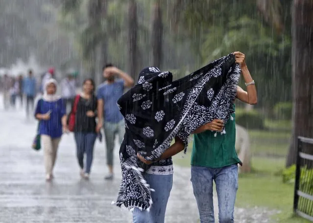 Girls try to cover themselves by a stole during a heavy rain shower in Chandigarh, India, July 10, 2015. (Photo by Ajay Verma/Reuters)