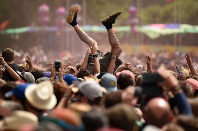 Revellers help a man crowdsurf as they watch The Slaves perform on The Other Stage at the Glastonbury Festival of Music and Performing Arts on Worthy Farm near the village of Pilton in Somerset, South West England, on June 30, 2019. (Photo by Oli Scarff/AFP Photo)