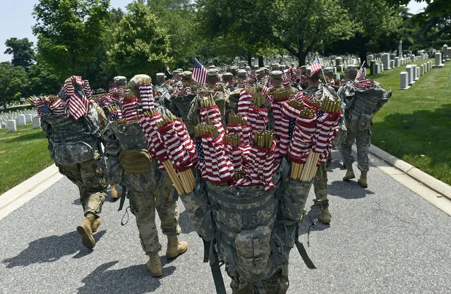 Members of the Old Guard prepare to place flags in front of every headstone at Arlington National Cemetery in Arlington, Va., Thursday, May 26, 2016. Soldiers were to place nearly a quarter of a million U.S. flags at the cemetery as part of a Memorial Day tradition. (Photo by Susan Walsh/AP Photo)