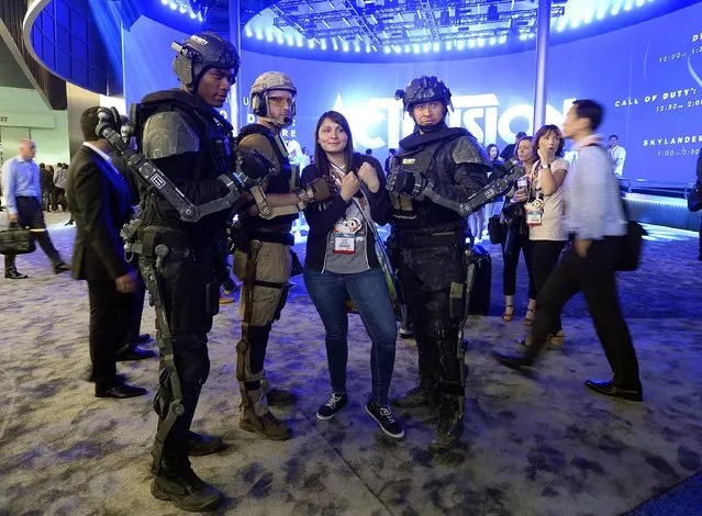 An attendee poses with men dressed as characters from the new multiplayer action game "Call of Duty: Advanced Warfare", in front of the Activision booth at the 2014 Electronic Entertainment Expo, known as E3, in Los Angeles, June 10, 2014.  REUTERS/Kevork Djansezian