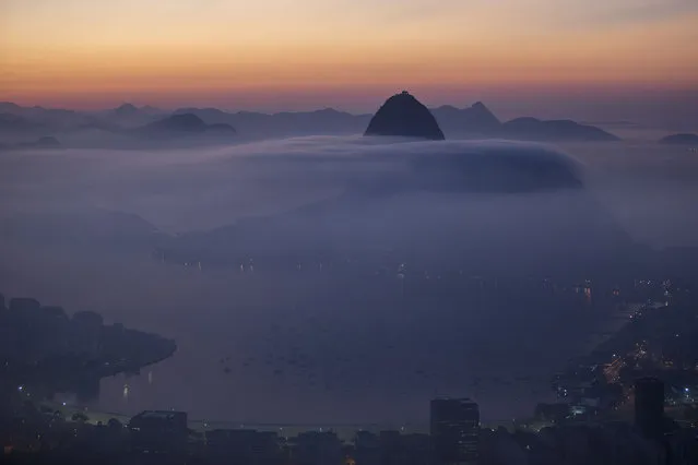 Sugarloaf Mountain and the Guanabara Bay are seen in a blanket of early morning fog as the sun begins to rise in Rio de Janeiro, Brazil, Friday, May 16, 2014. As opening day for the World Cup approaches, people continue to stage protests, some about the billions of dollars spent on the World Cup at a time of social hardship, but soccer is still a unifying force. The international soccer tournament will be the first in the South American nation since 1950. (Photo by Felipe Dana/AP Photo)